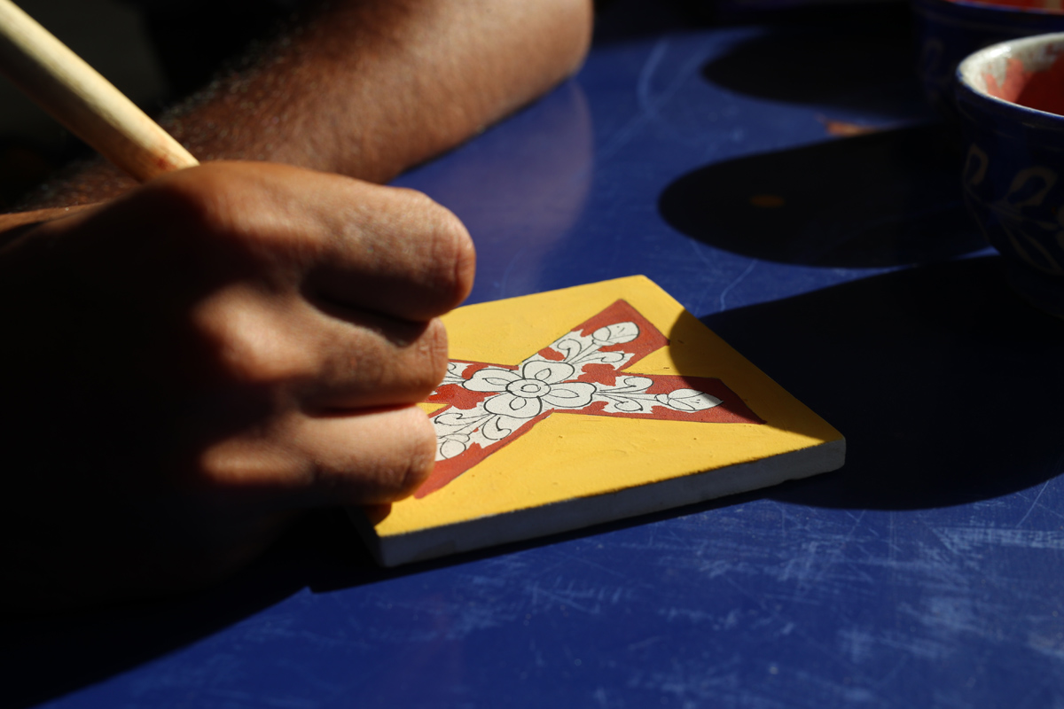 Students painting on blue pottery tile